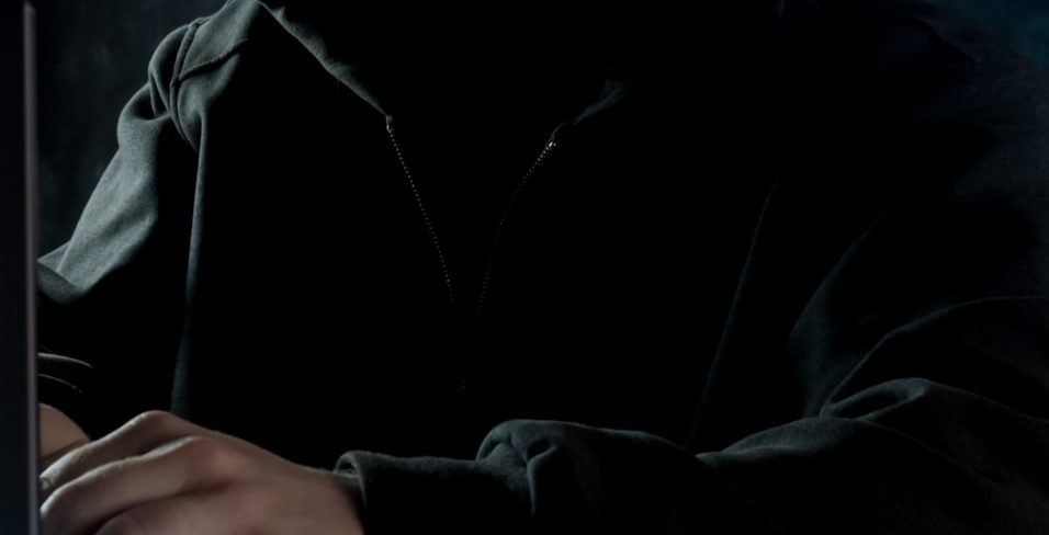 a man in a hoodie using a laptop computer